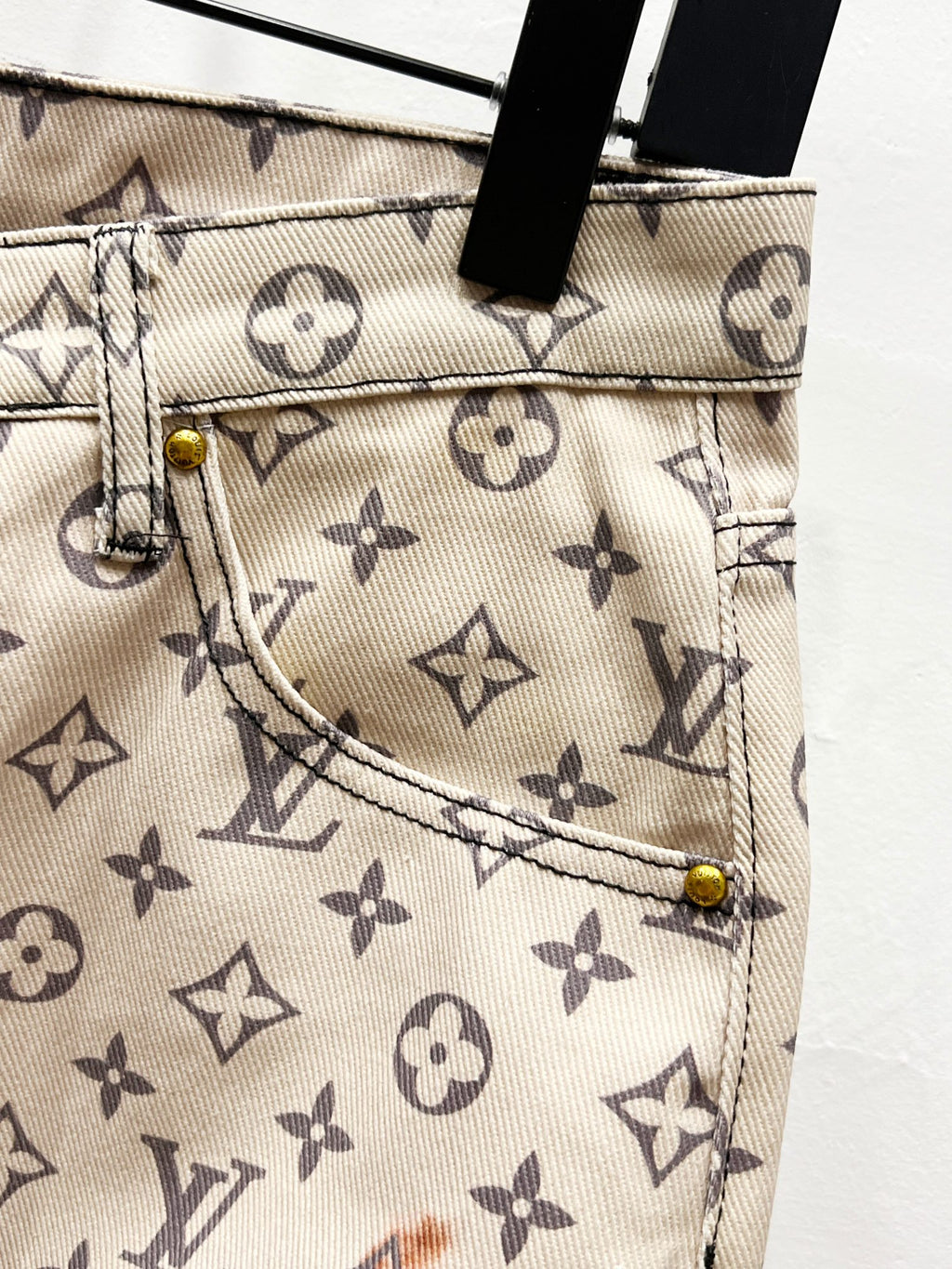 Back pocket detail on monogram print trousers with beige fabric and metal rivets