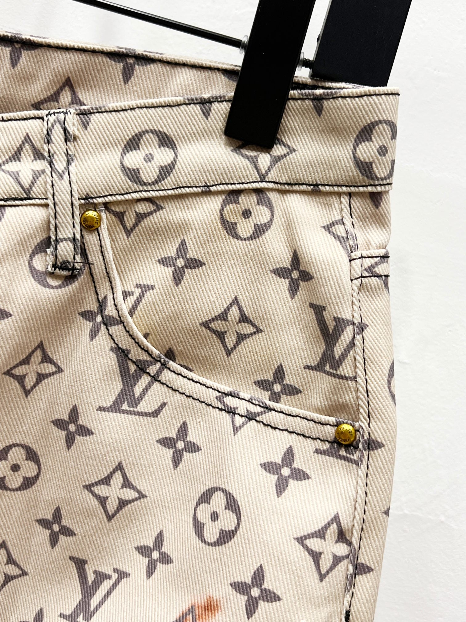 Back pocket detail on monogram print trousers with beige fabric and metal rivets