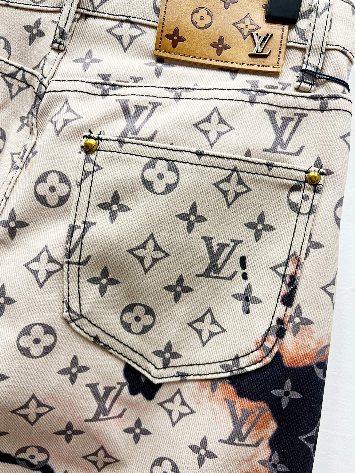 Front pocket close-up on monogram print trousers with beige lining and contrast stitching