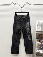 Dark denim pants on hanger with Balenciaga vertical text logo on right side