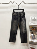 Dark denim pants on hanger with Balenciaga text logo on right leg