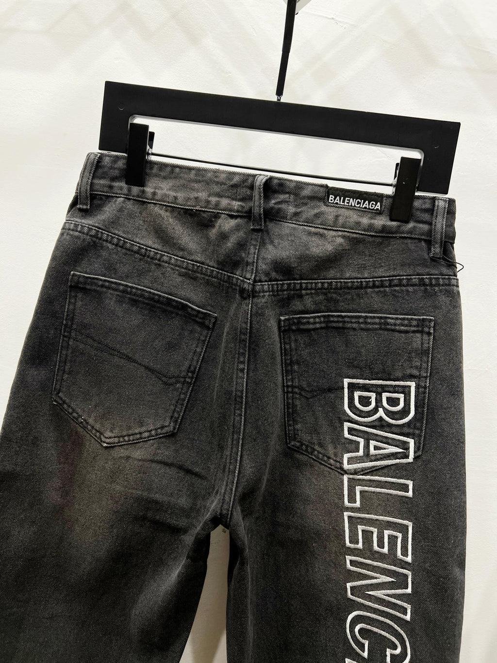 Dark denim pants on hanger with back pockets and Balenciaga logo print