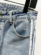 Light blue denim pocket close-up with metal rivet and contrast topstitching