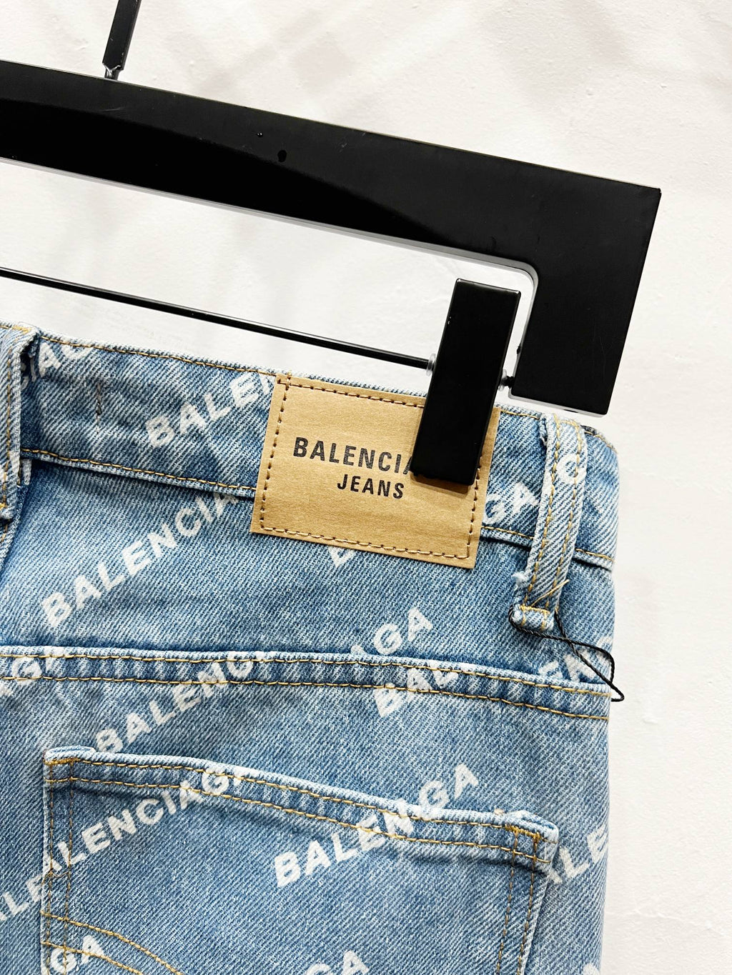 Denim jeans waistband close-up with tan patch label and stitched logo detailing