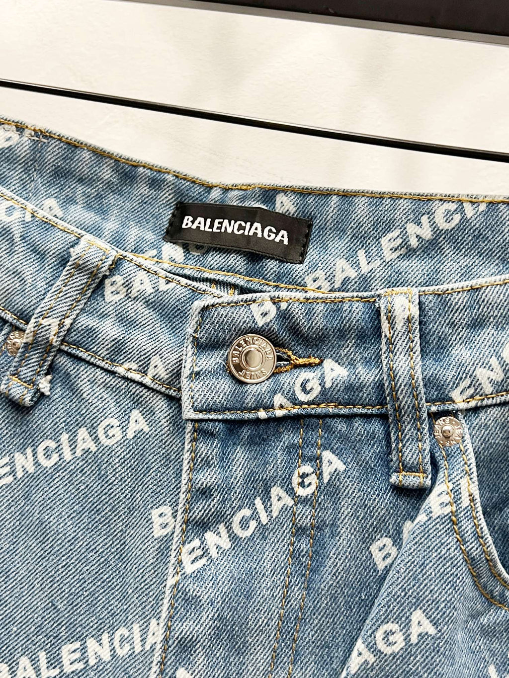 Back pocket close-up with BALENCIAGA patch, metal button, and logo printed denim