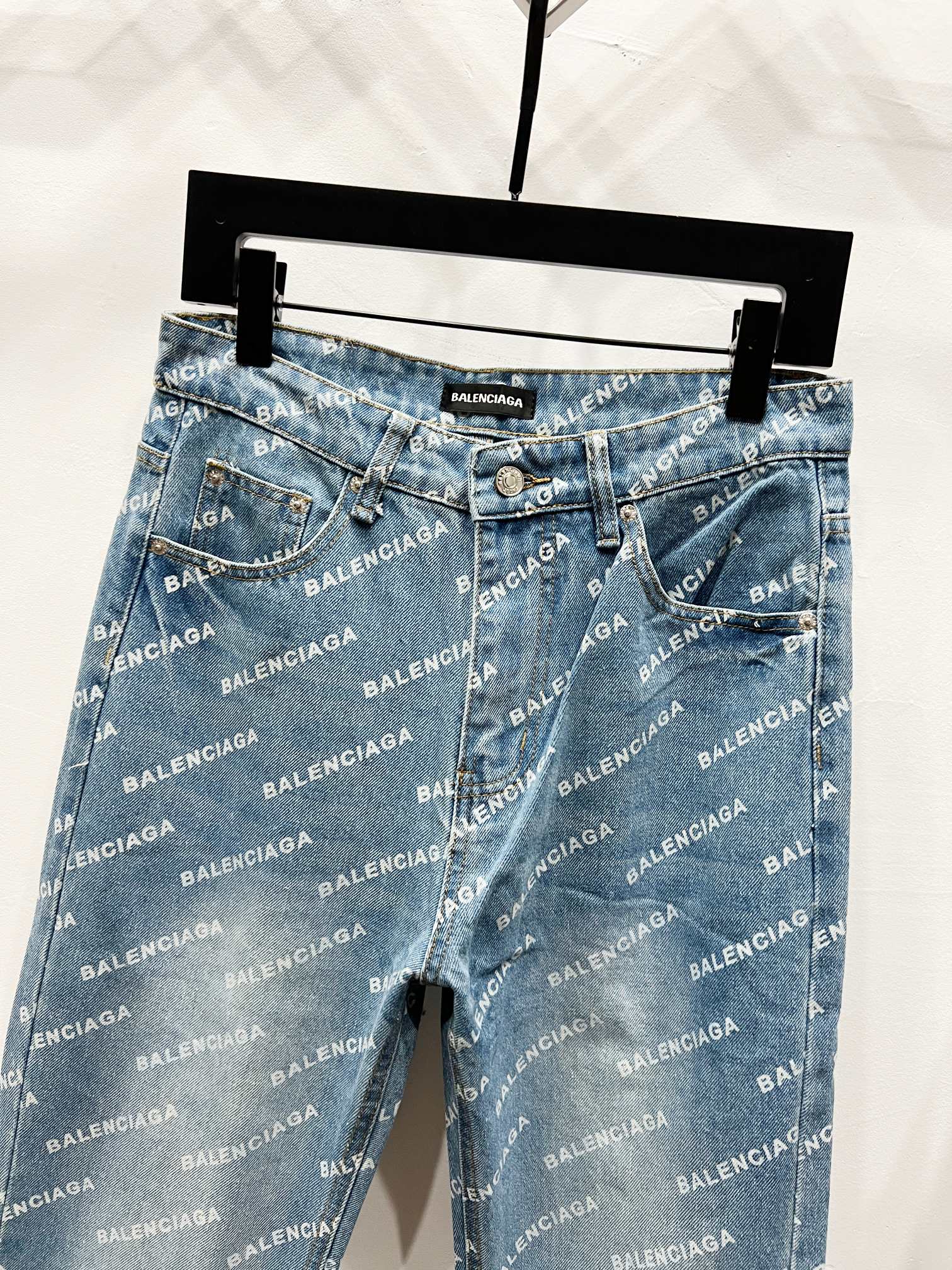 Blue logo-print denim pants hanging on a rack, straight leg and belt loops