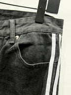Black denim pants waistband with front button, belt loops, and vertical side stripe
