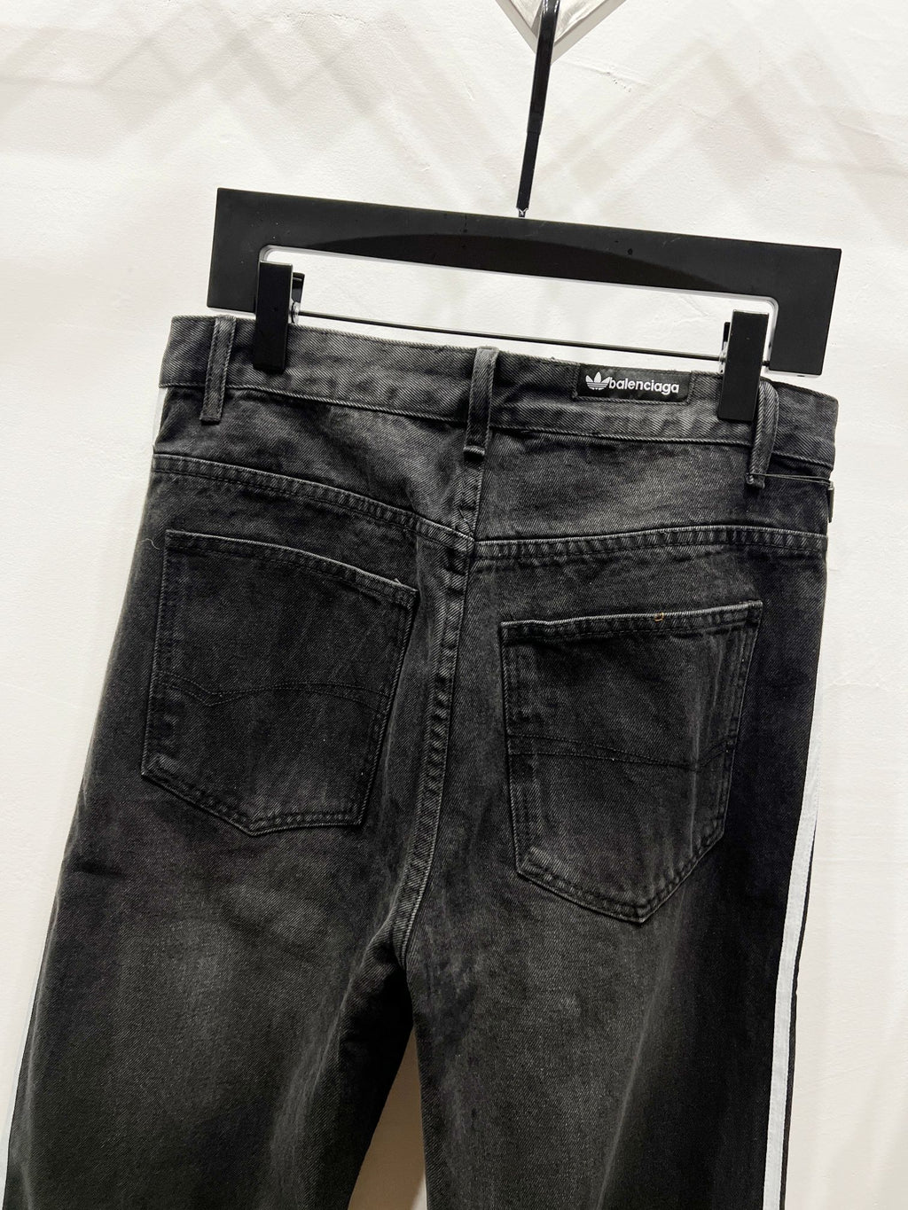 Black denim jeans with straight legs, front pockets, and waistband brand patch