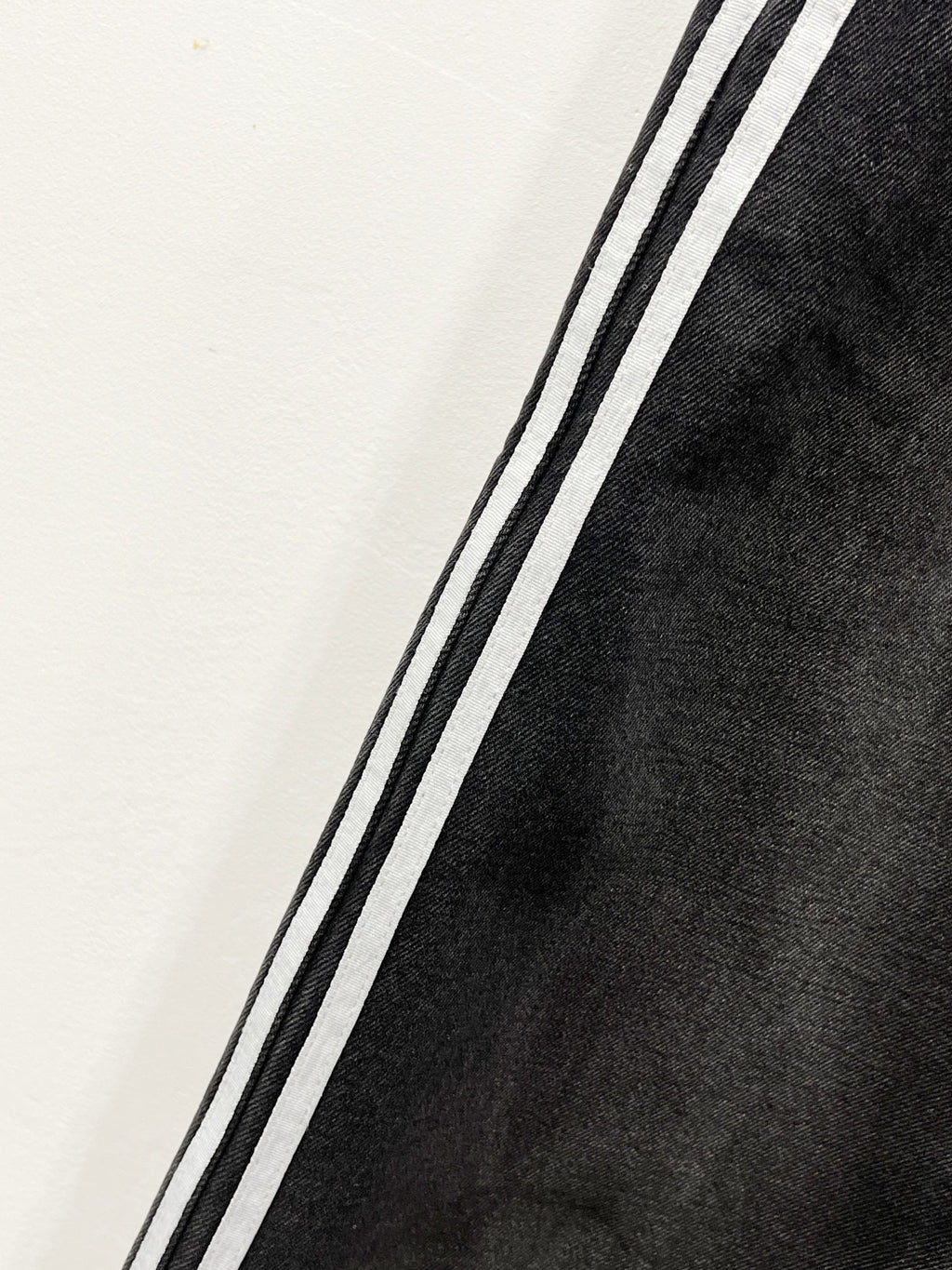 Black denim pants leg with contrasting side stripe along the seam