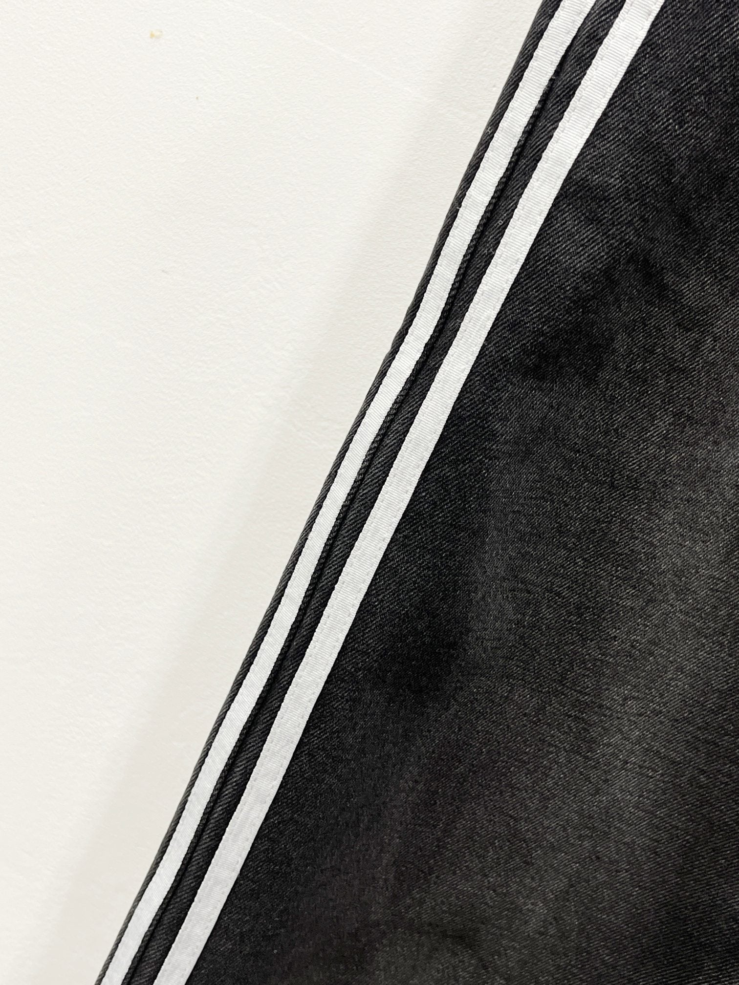 Black denim pants leg with contrasting side stripe along the seam