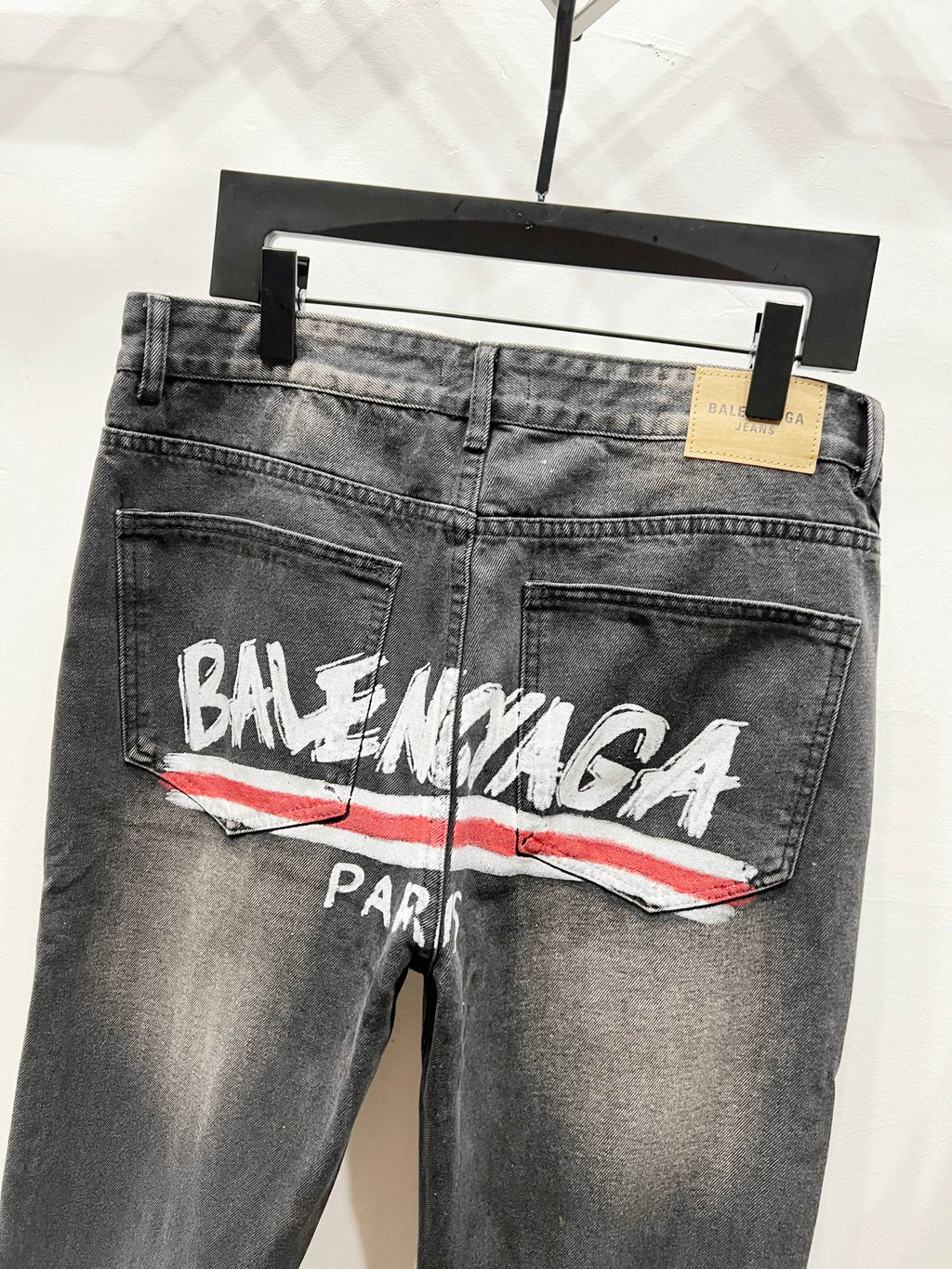 Grey-wash denim pants with Balenciaga Paris logo and red stripe, front close-up