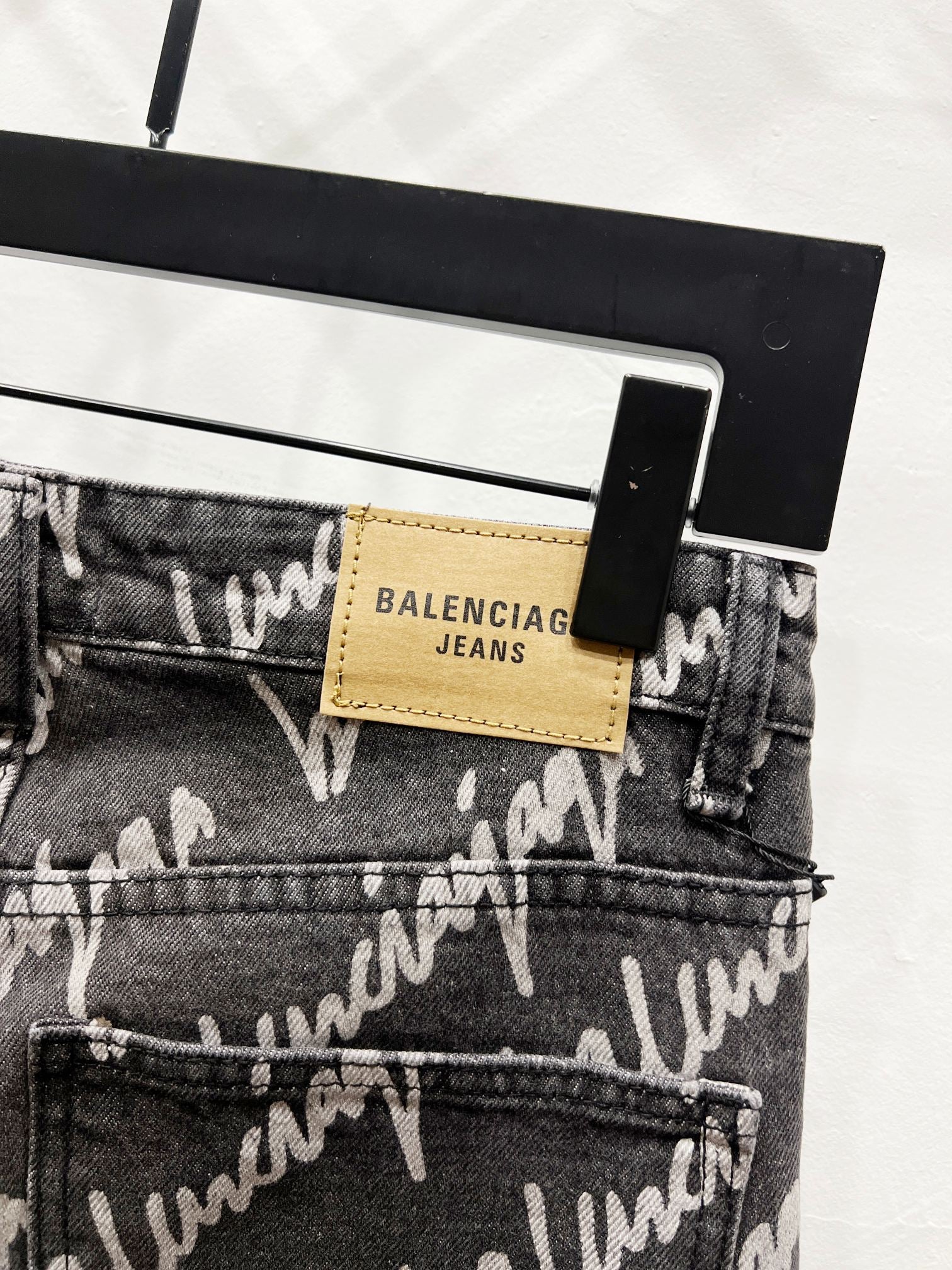 Black denim jeans with 'BALENCIAGA JEANS' leather patch on waistband and button fly