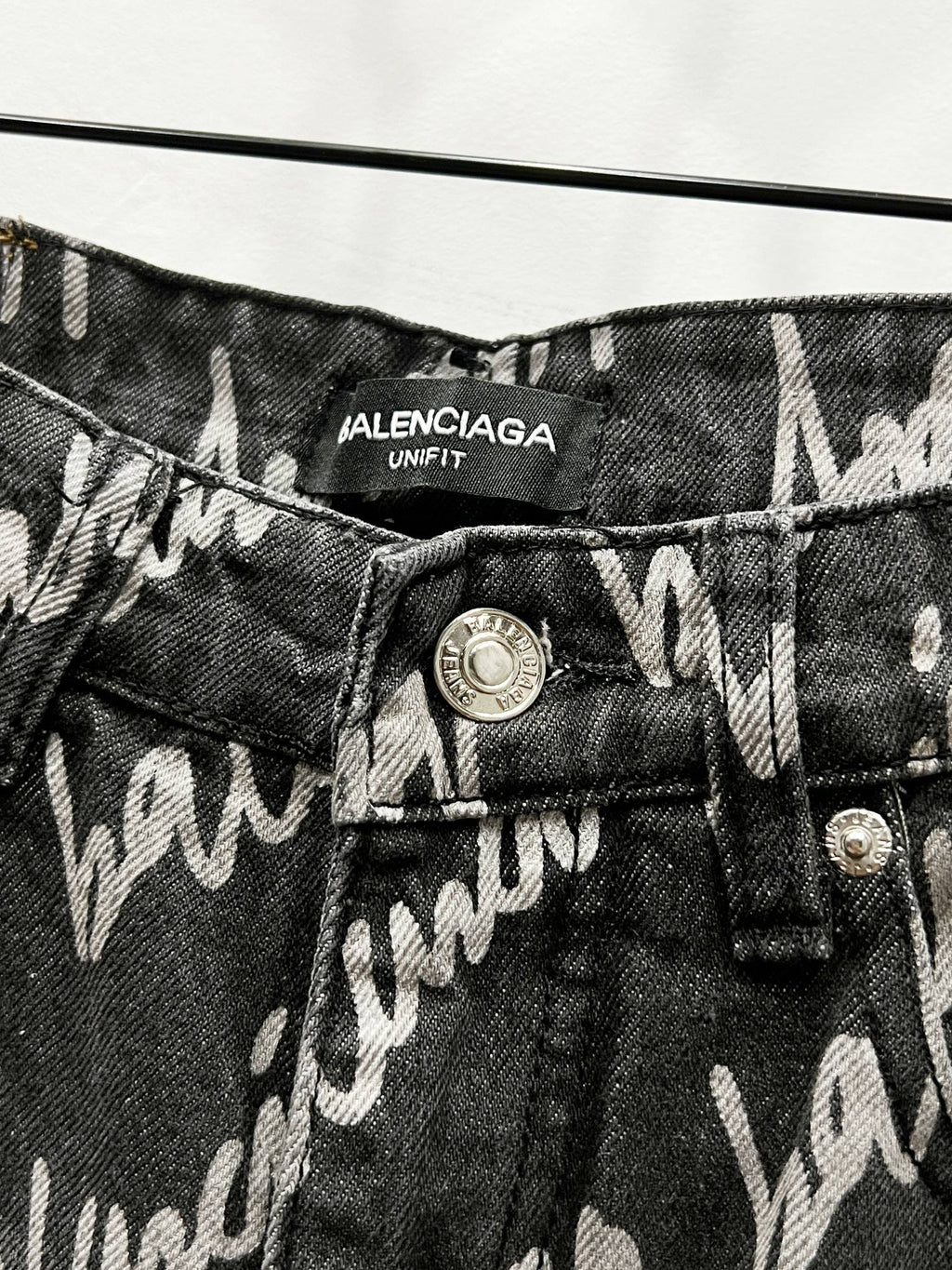 Black denim jeans with Balenciaga Uniform label and metal button close-up