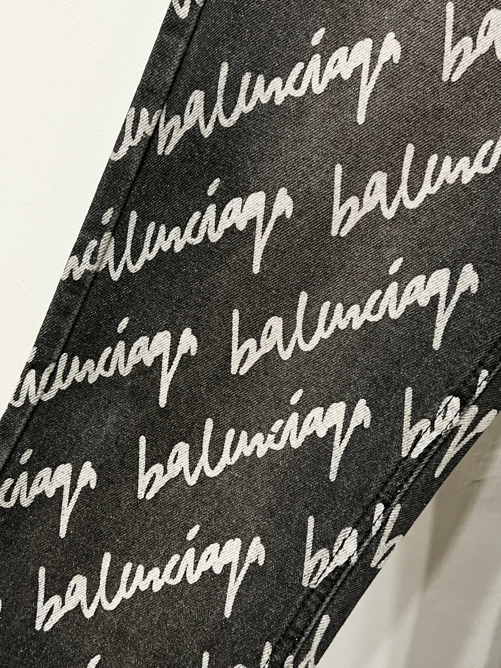 Black denim fabric with white Balenciaga script pattern, fabric close-up