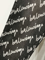 Black denim fabric with white Balenciaga script pattern, fabric close-up