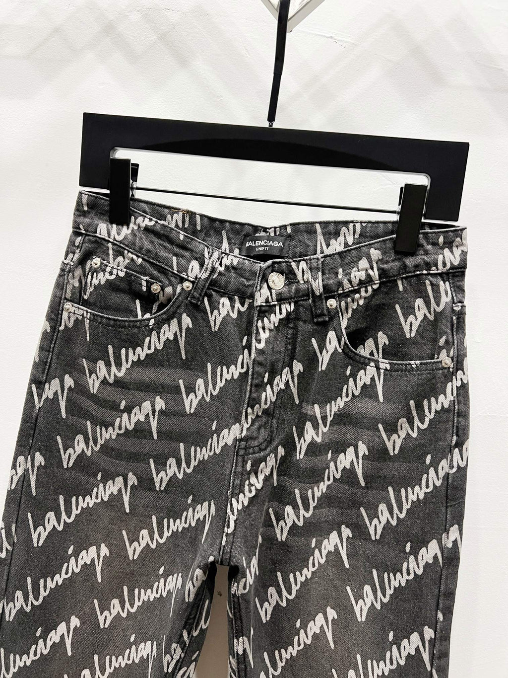 Black denim jeans with allover Balenciaga script print, front view with belt loops