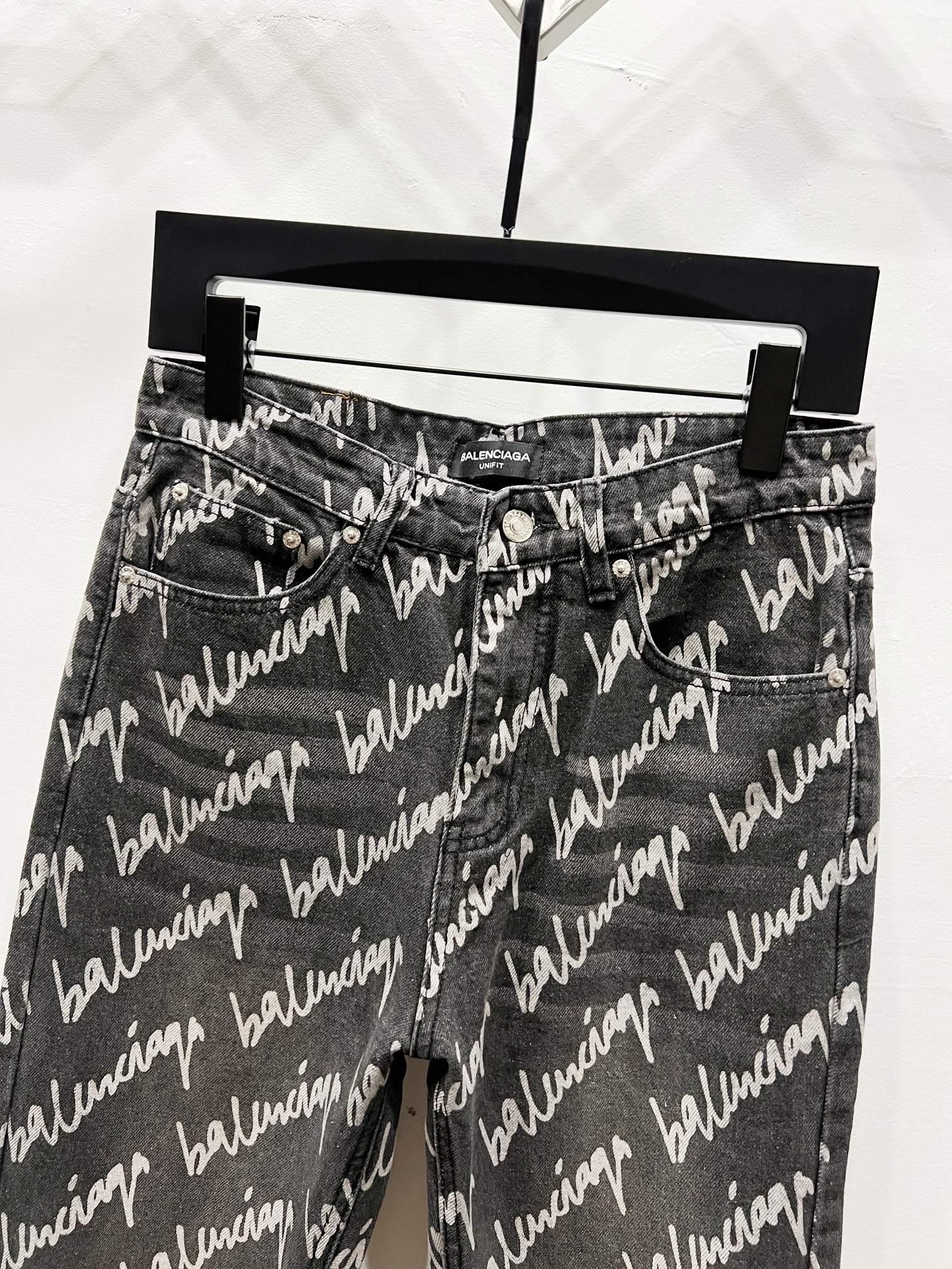 Black denim jeans with allover Balenciaga script print, front view with belt loops