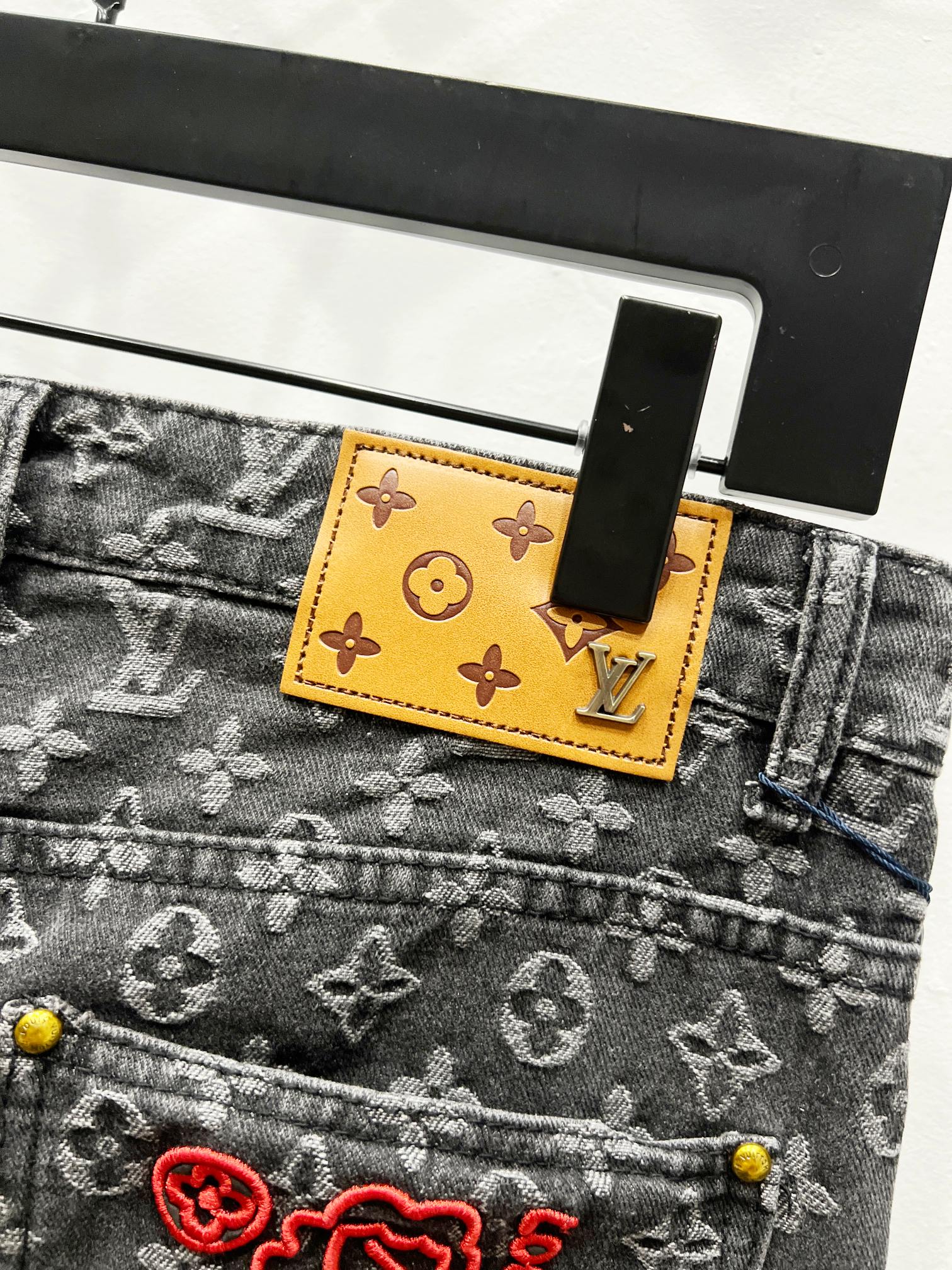 Louis Vuitton monogram denim jeans with yellow waist tag and red logo