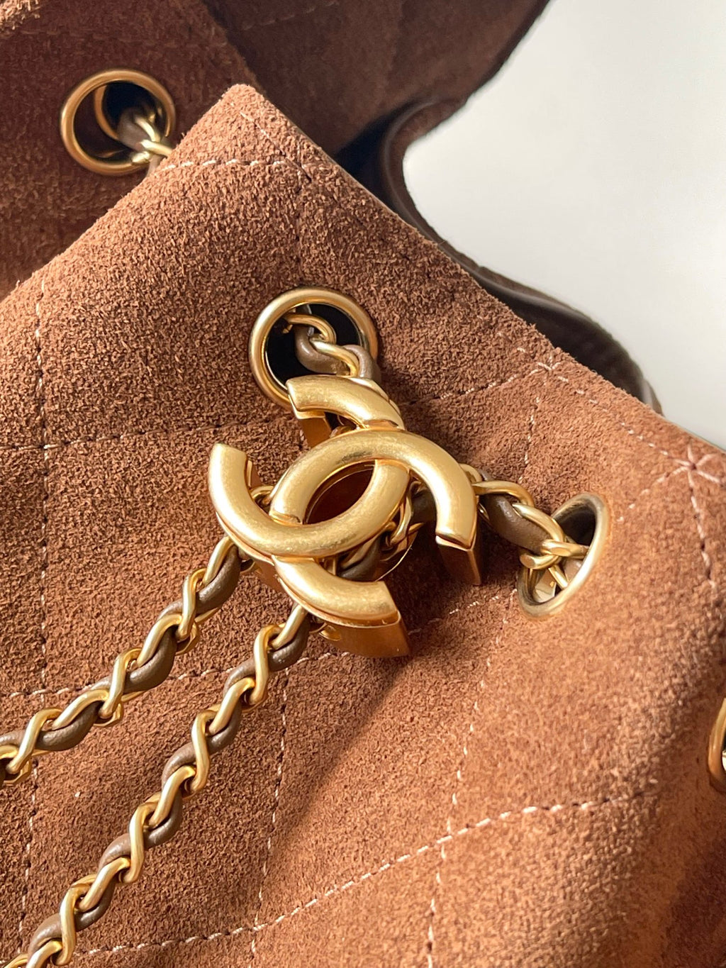 Gold chain and clasp hardware on tan-brown suede bag