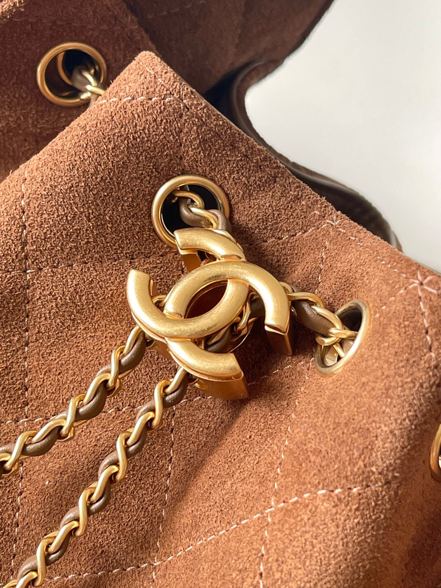 Gold chain and clasp hardware on tan-brown suede bag