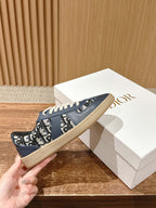 Navy blue low-top sneakers with white laces beside a white Dior shoebox