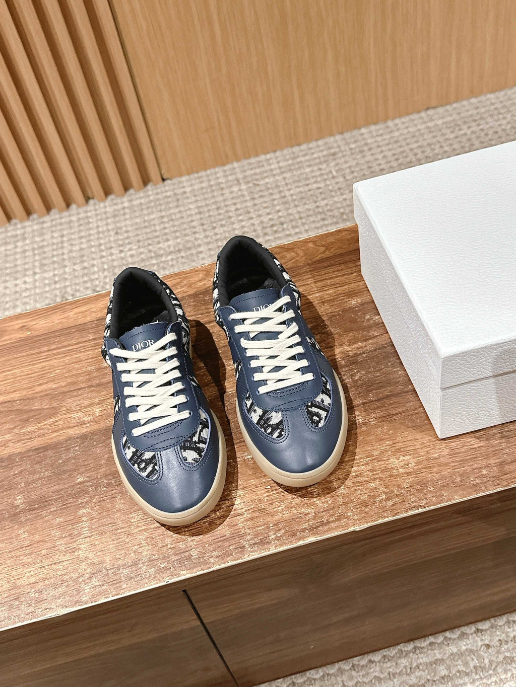 Navy blue low-top sneakers with white laces and patterned logo panels