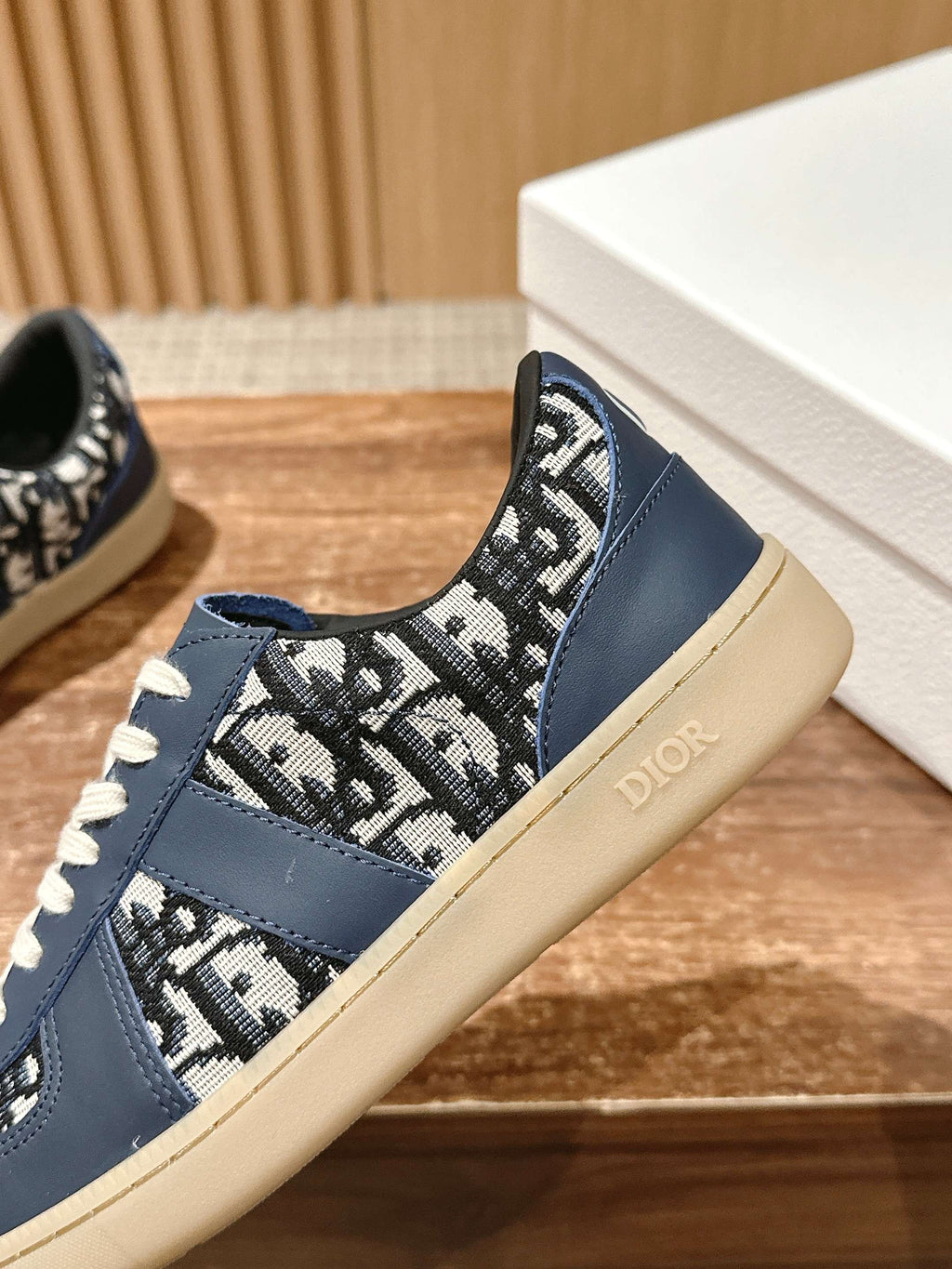 Navy blue low-top sneakers with white laces and black-and-white patterned collar