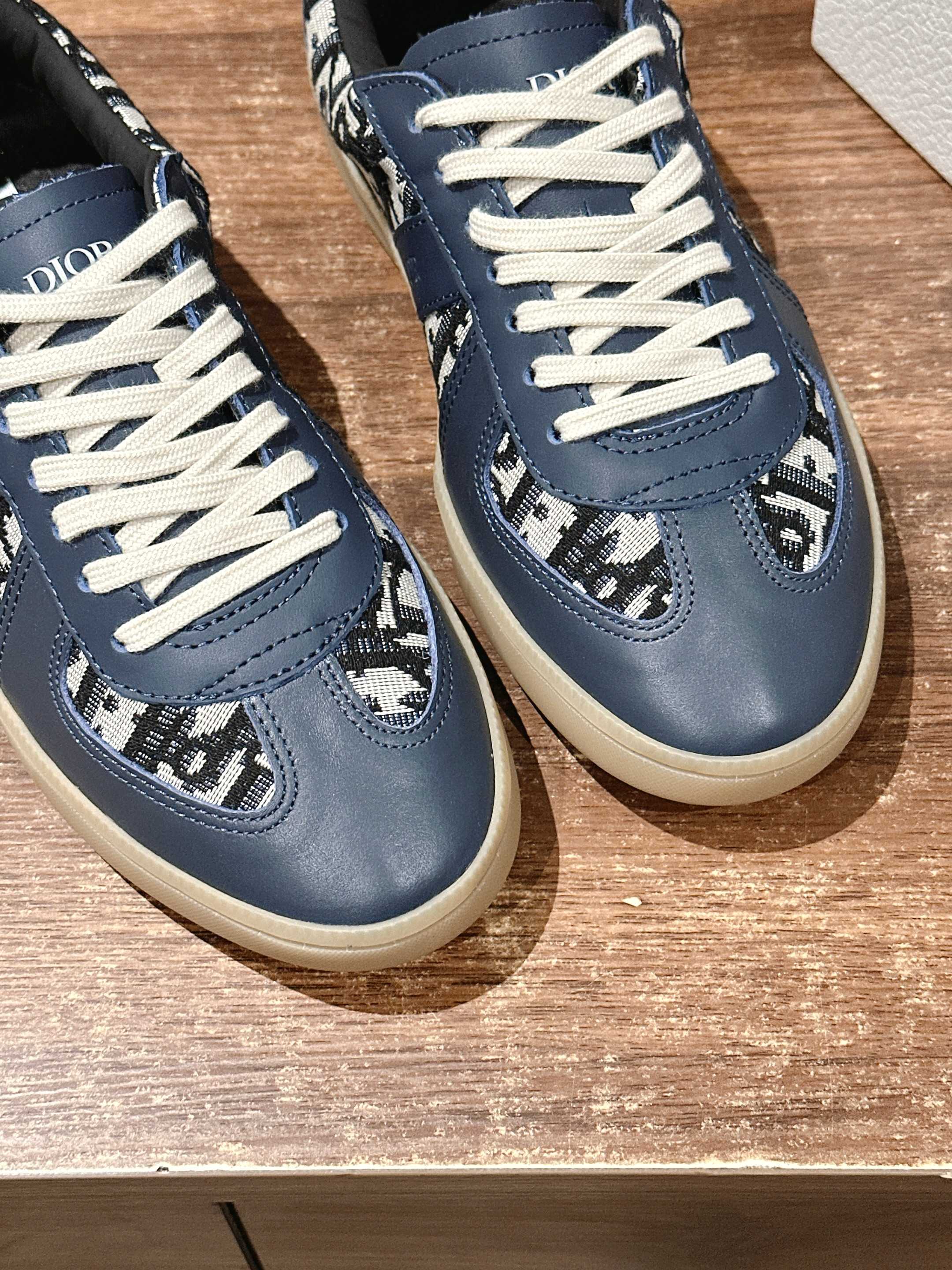 Pair of navy blue low-top sneakers with white laces and patterned toe panels