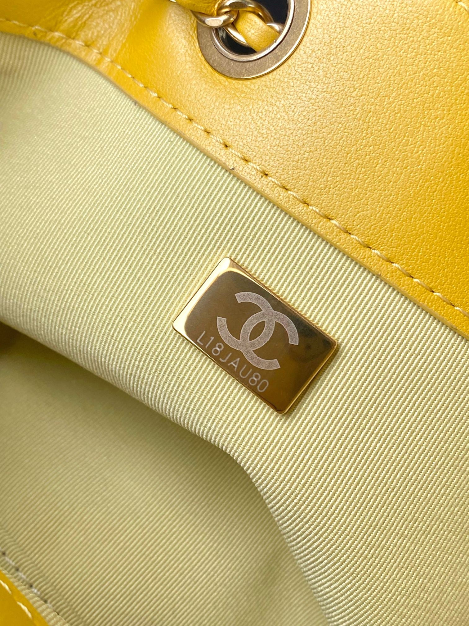 Chanel interior label plaque on yellow bag lining with gold-tone hardware detail