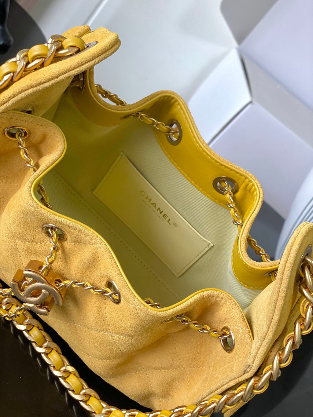 Chanel bag interior view in yellow with logo patch, gold-tone hardware, and pockets
