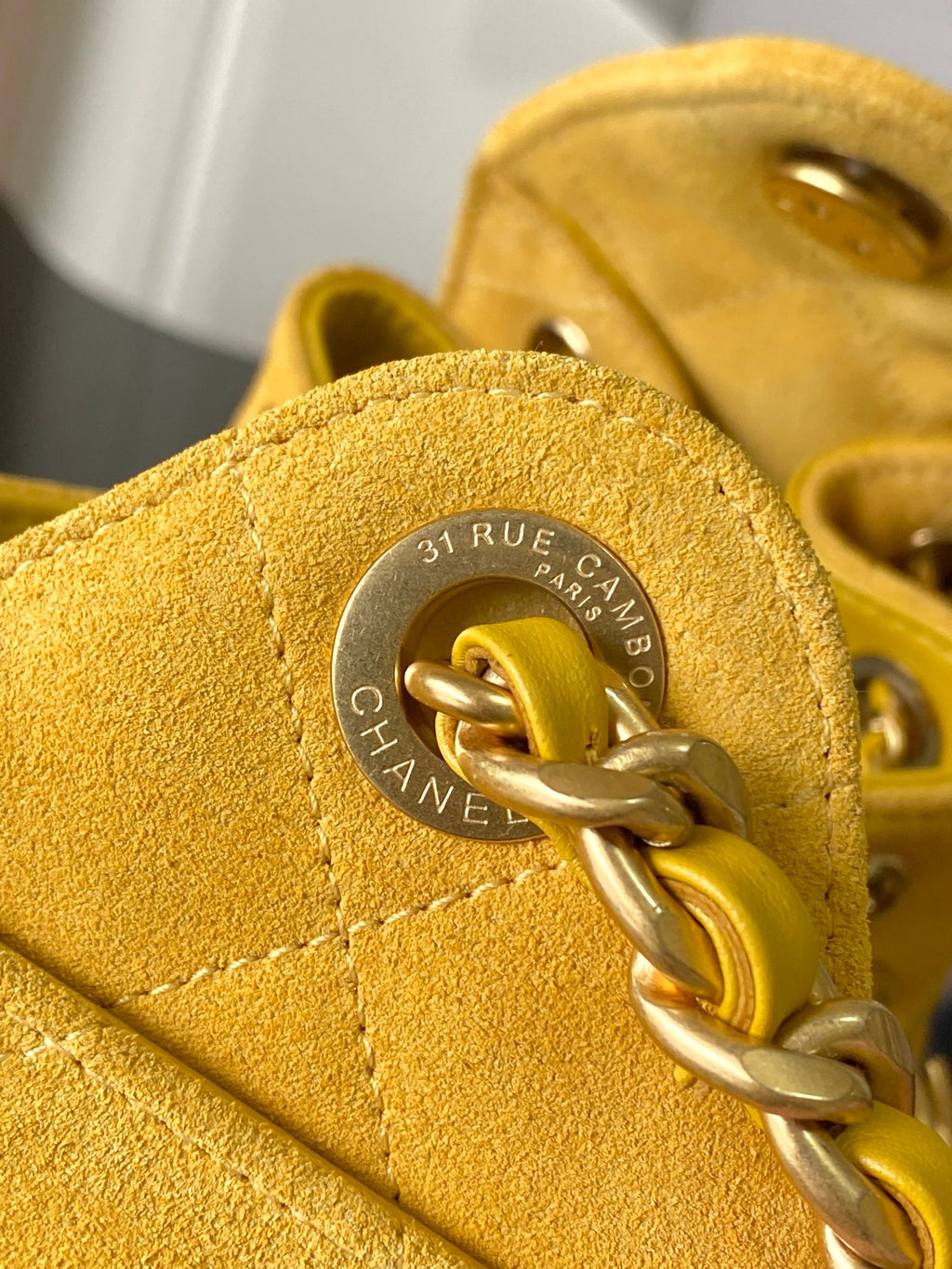 Chanel bag clasp close-up on yellow leather with circular engraved emblem