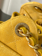 Chanel bag clasp close-up on yellow leather with circular engraved emblem