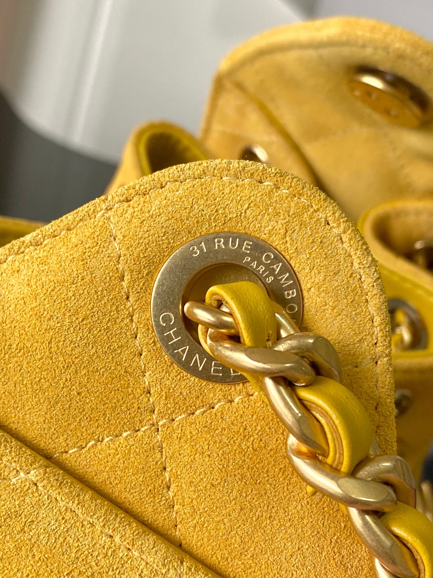 Chanel bag clasp close-up on yellow leather with circular engraved emblem