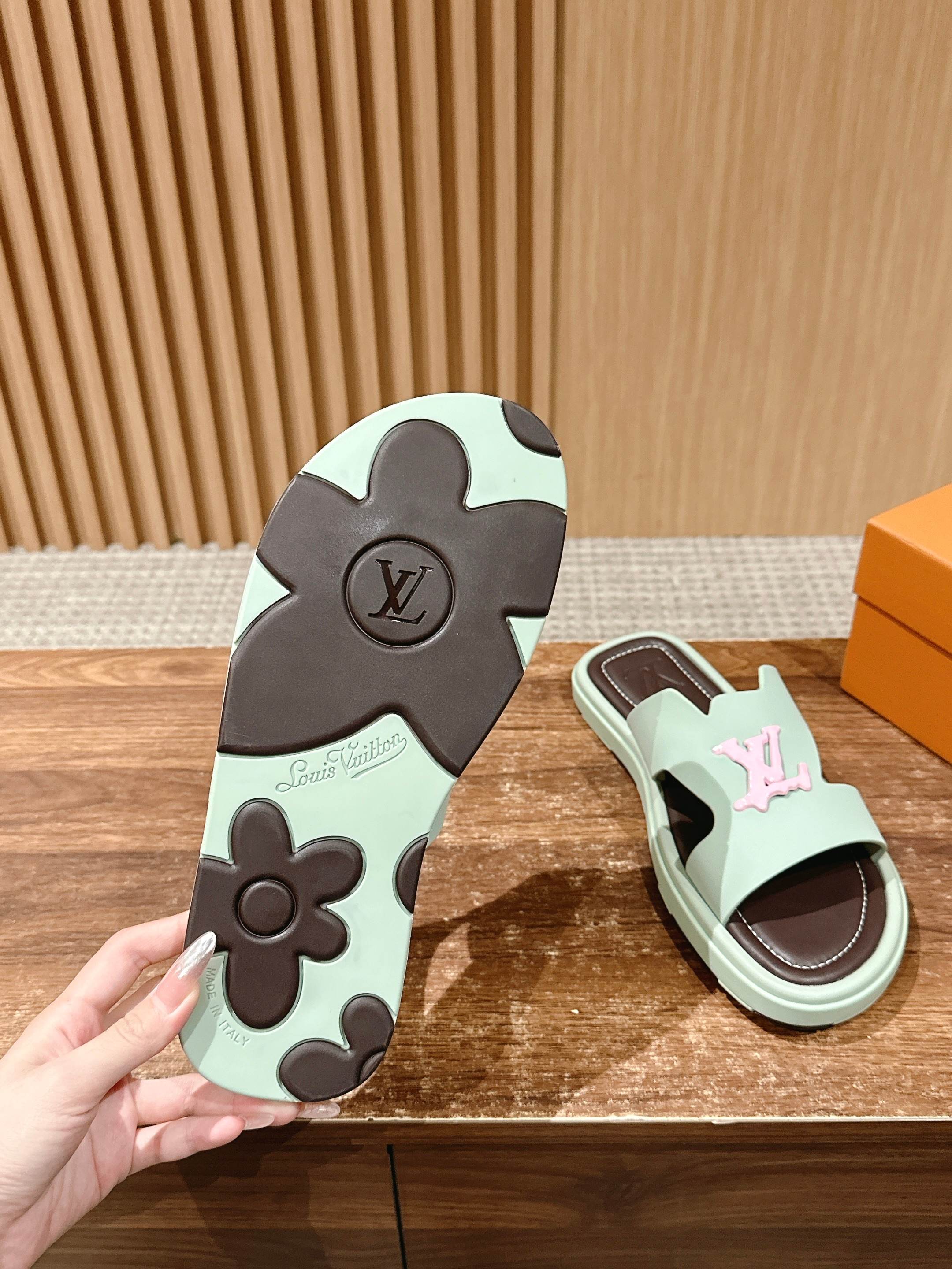 Sandal outsole and mint slide sandal with pink LV emblem; hand holding sole