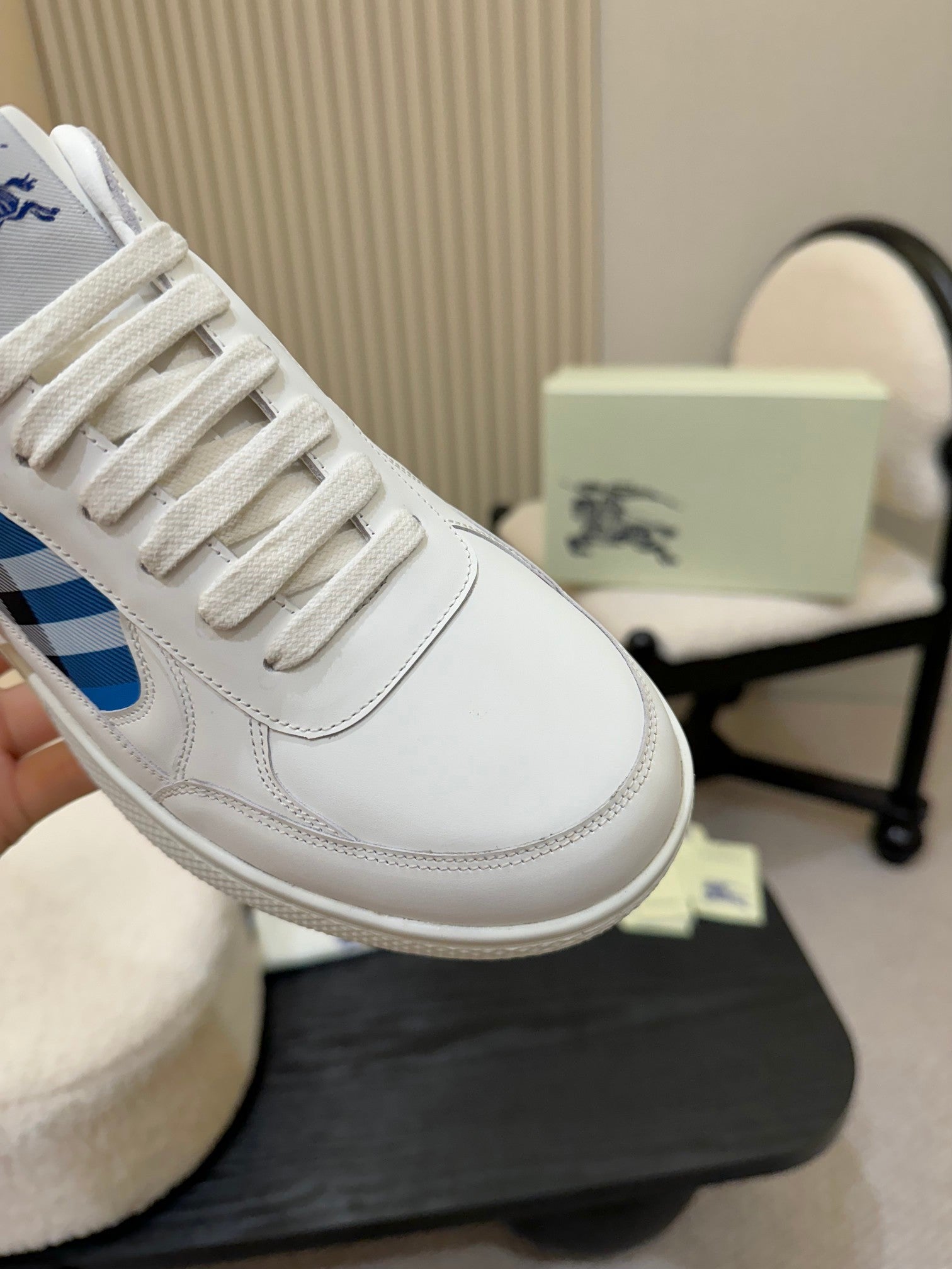 White sneaker close-up: lace-up front with blue plaid accent