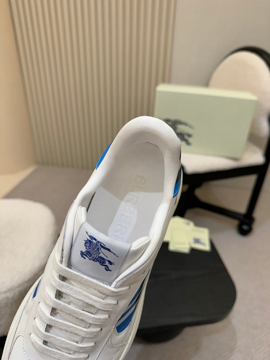 White sneaker interior view with blue logo print near collar