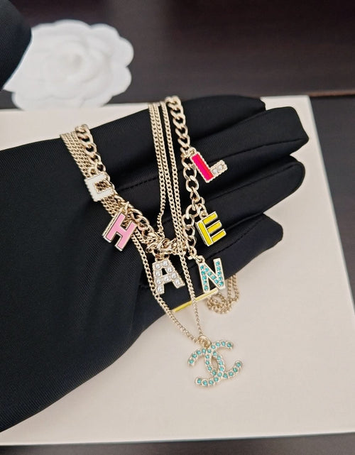 Gold-tone layered Chanel chain necklace with multicolor letter charms and CC pendant