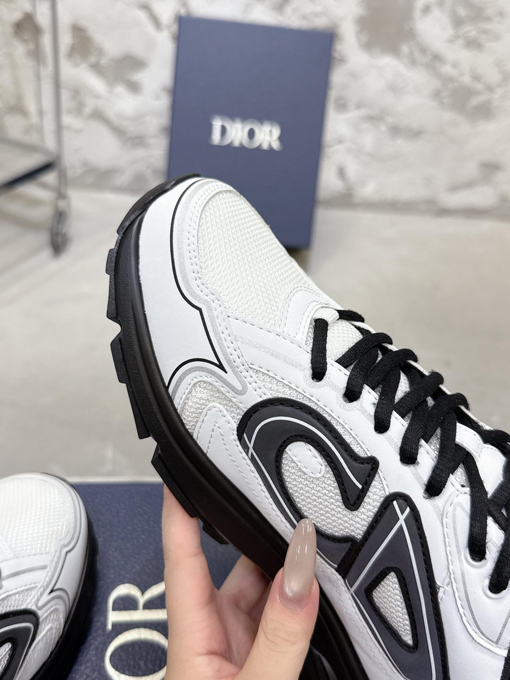 White Dior sneaker with black trim and lace-up, close-up side view
