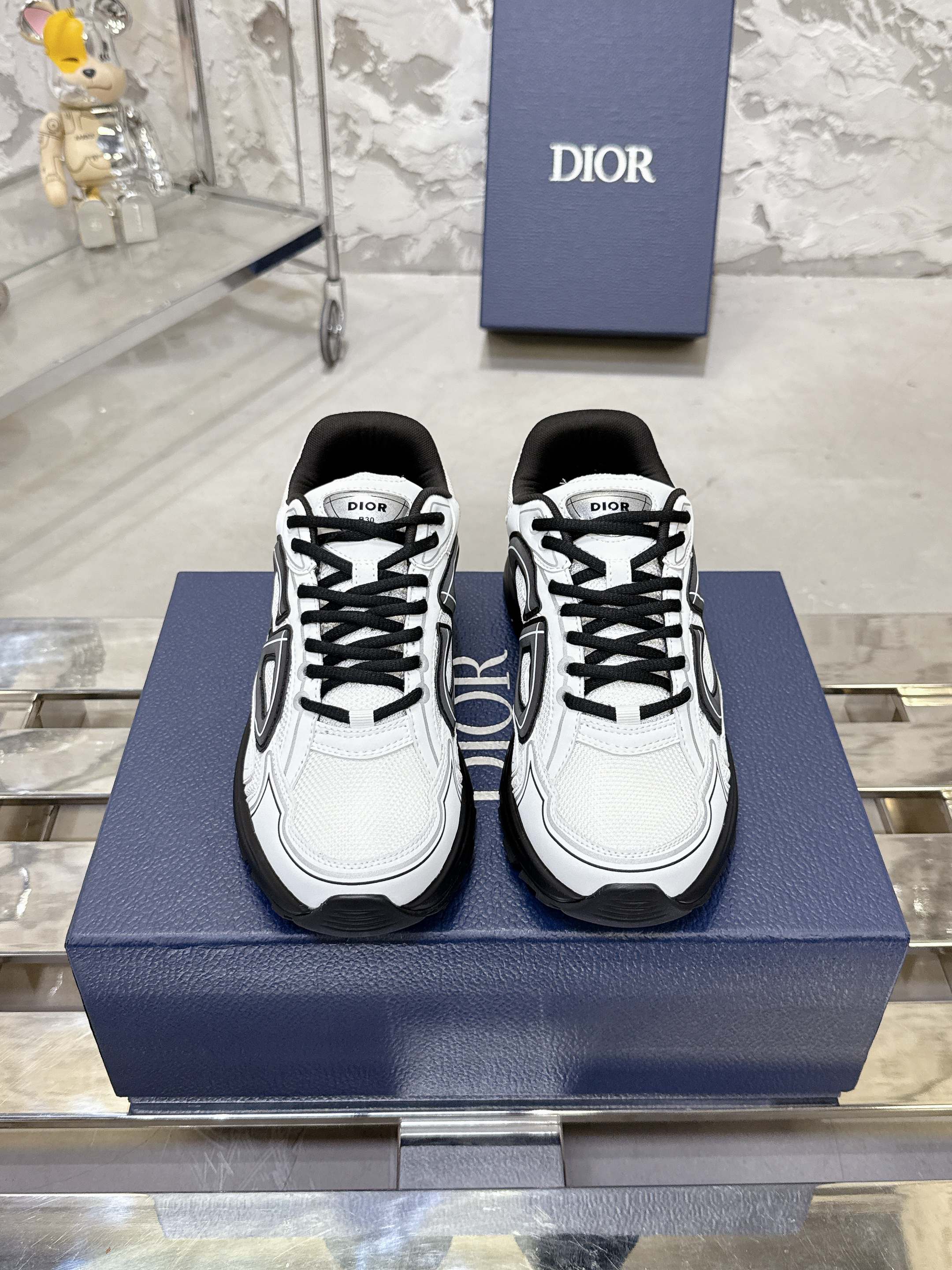 White Dior lace-up sneakers with black chunky soles, front view pair on box