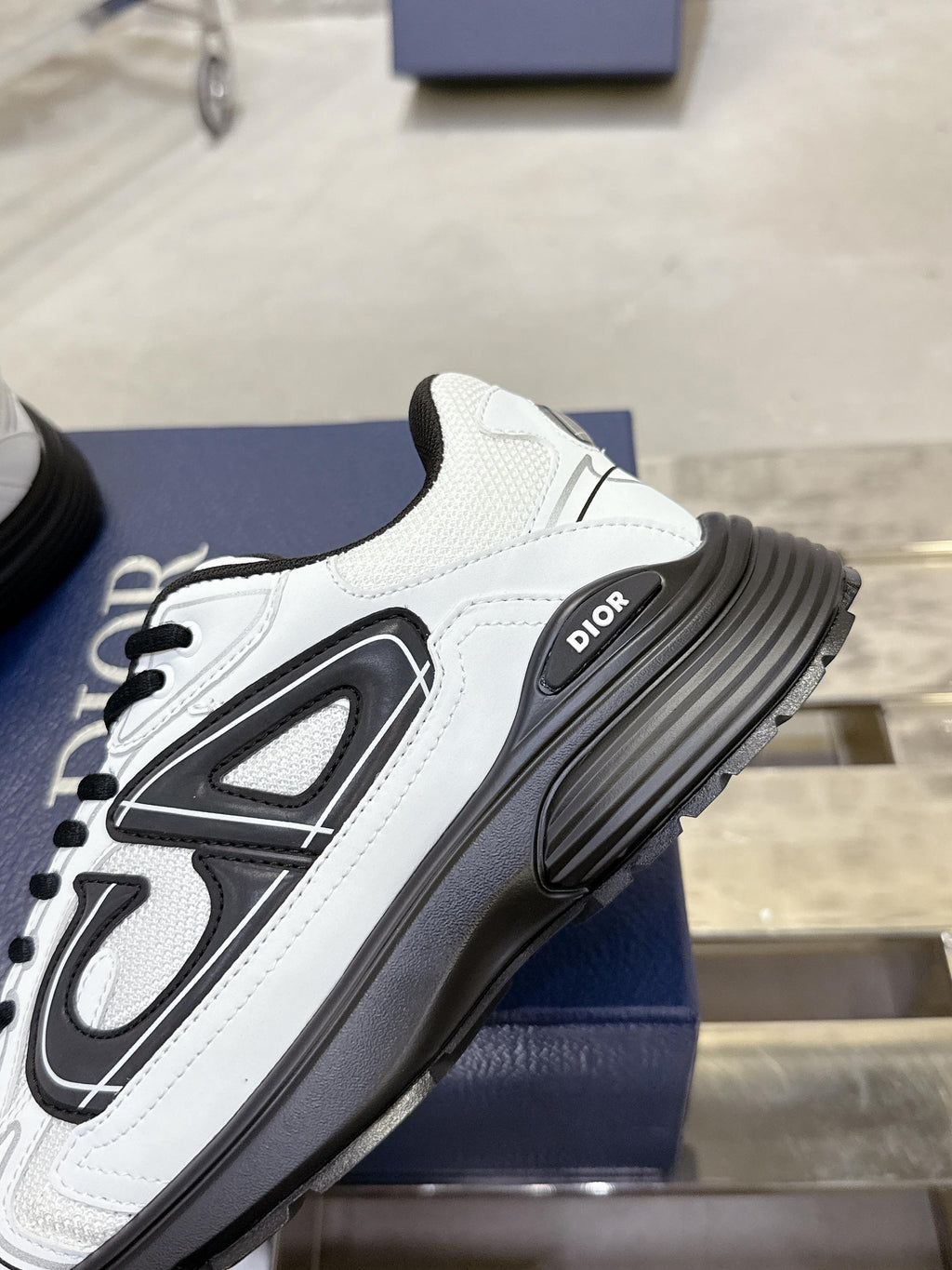White Dior lace-up sneaker with black chunky sole, angled side view