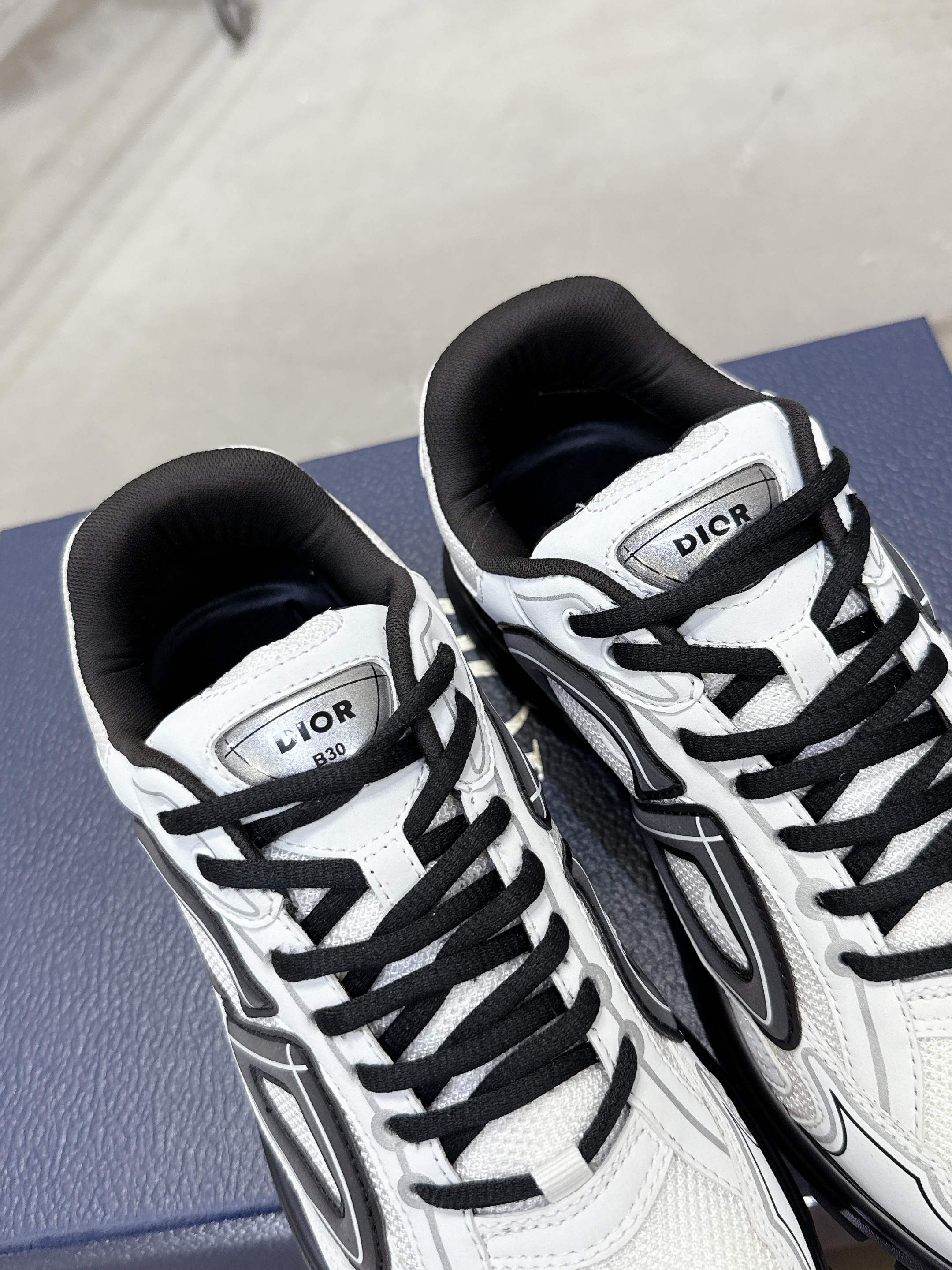 White Dior lace-up sneakers with black laces, close-up pair view