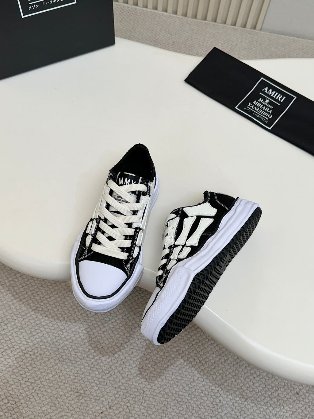 Black and white low-top lace-up sneakers with white rubber sole and patterned panels