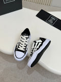 Black and white low-top lace-up sneakers with white rubber sole and patterned panels