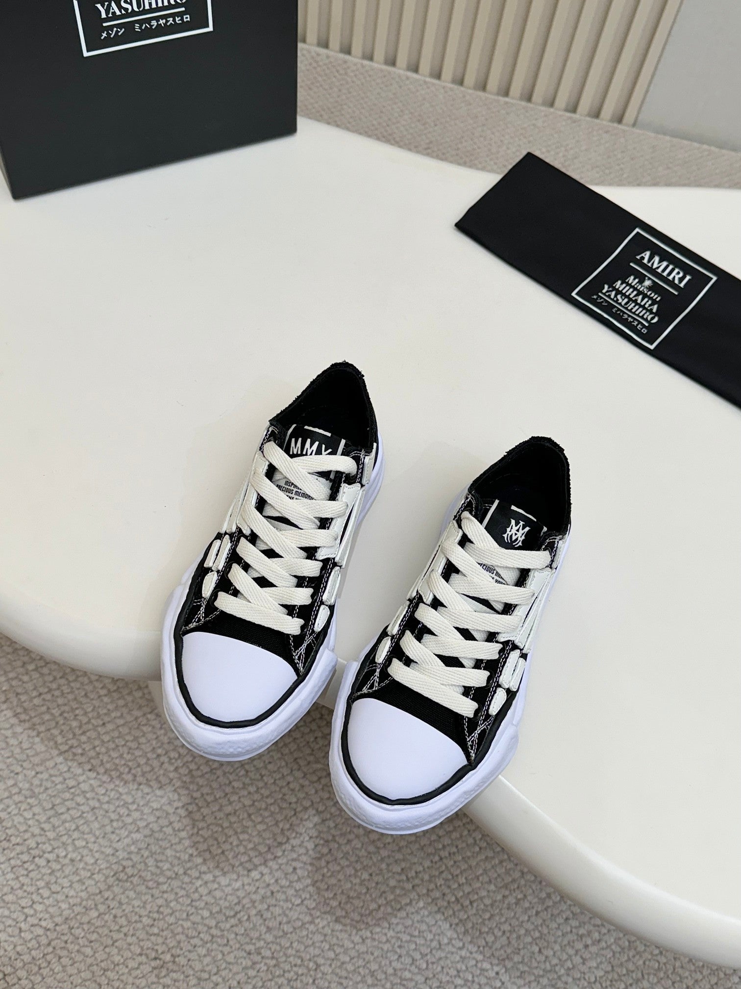Black low-top lace-up sneakers with white laces, white midsole, and textured trim