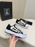 Pair of black and white low-top sneakers with bold panel design and white platform sole