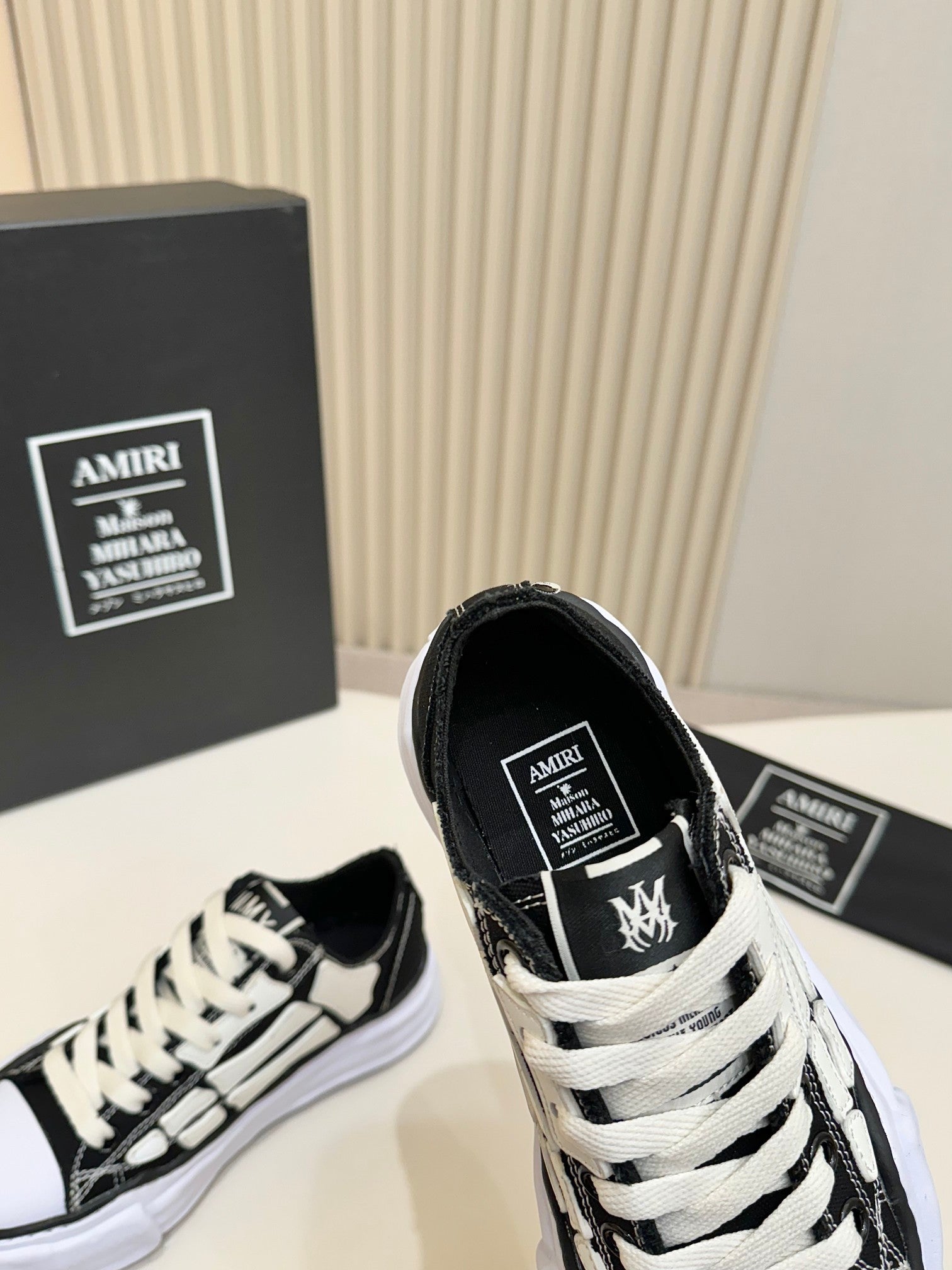 Black and white low-top sneakers, close-up of tongue label, lace-up with white trim