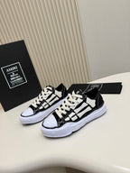 Black and white lace-up sneakers with white rubber sole, side view with contrast panels