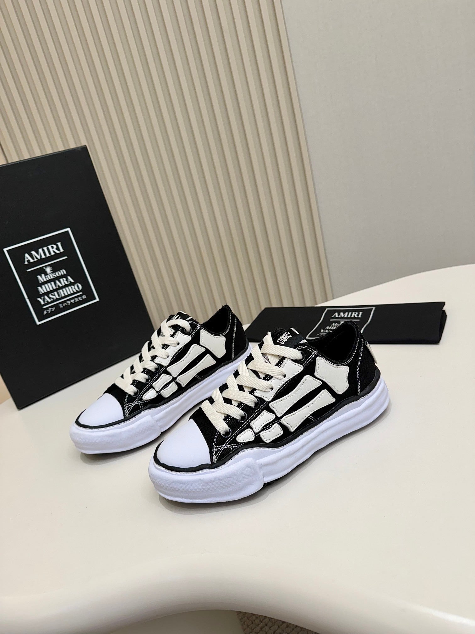 Black and white lace-up sneakers with white rubber sole, side view with contrast panels