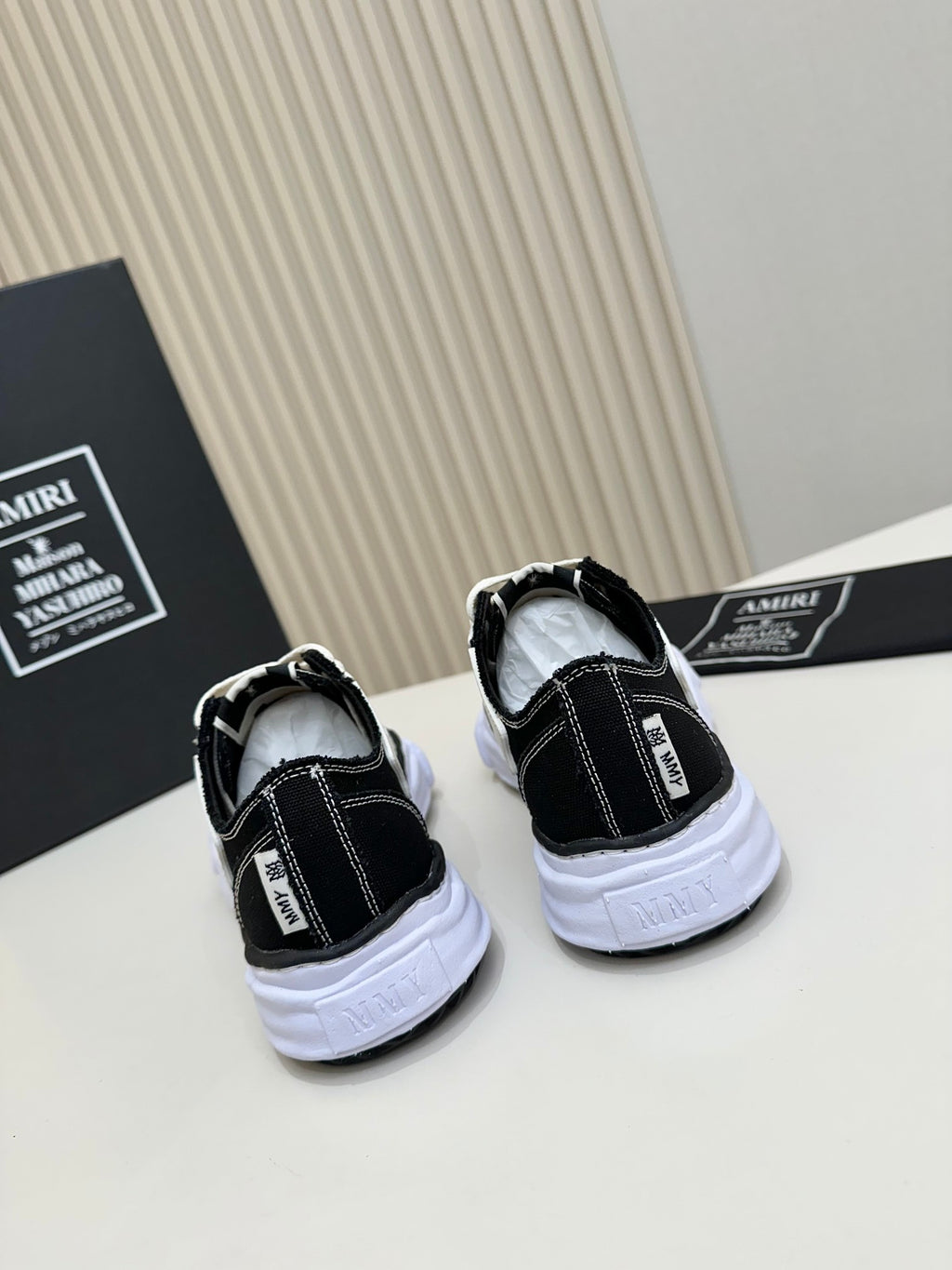 Back view of black and white low-top sneakers with white rubber soles