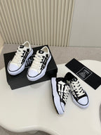 Pair of black and white lace-up sneakers on shoebox, one front and one side visible
